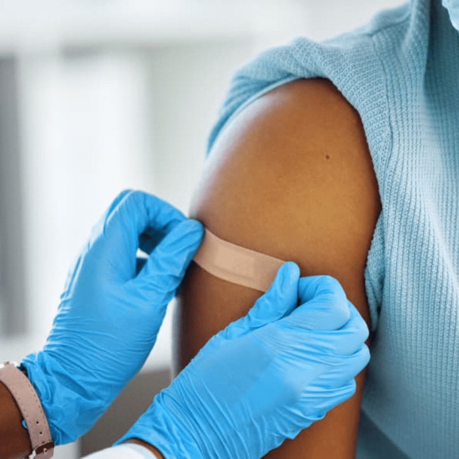 A doctor placing a band aid on arm after vaccination