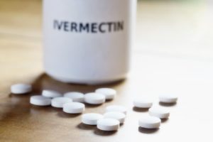 Pills on a table beside bottle labeled ‘Ivermectin’